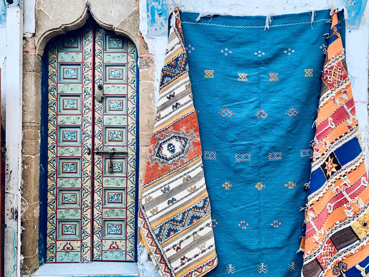 portfolio-03 Ornate doorway with vibrant woven rugs, showcasing cultural artistry and vibrant patterns.