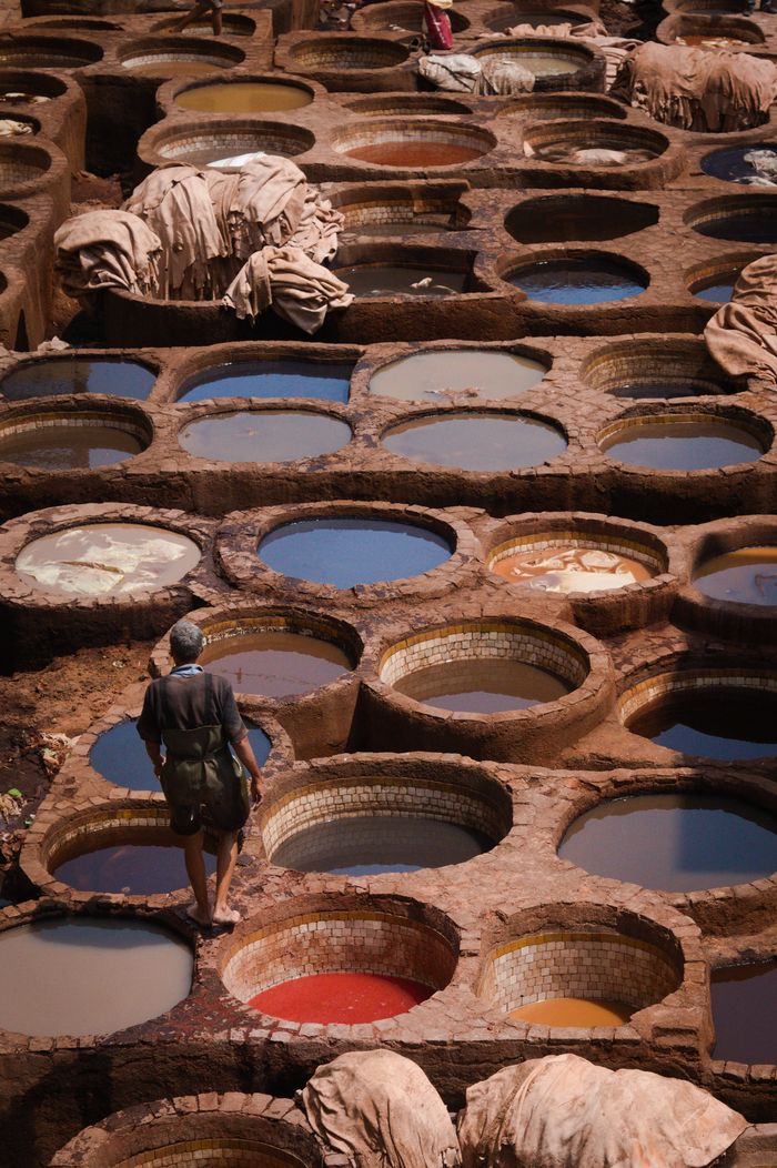 about-01 A worker walks through traditional leather tanning pits filled with colorful dye.