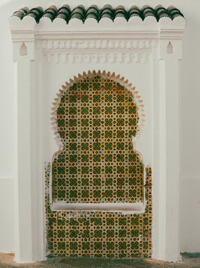 Capture of a traditional Moroccan mosaic wall with intricate Islamic art patterns on a building exterior.