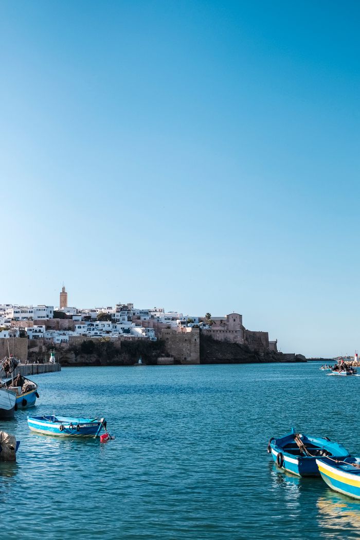 our-story-01 Picturesque coastal architecture of Rabat, Morocco with vibrant blue boats.